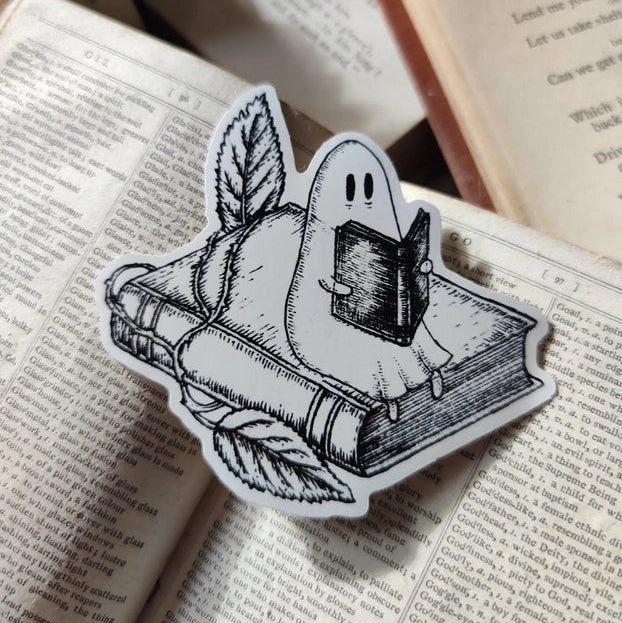 A studious little ghostie catching up on a bit of reading, on a lovely die-cut vinyl sticker, from an original ink illustration by Jon Turner.