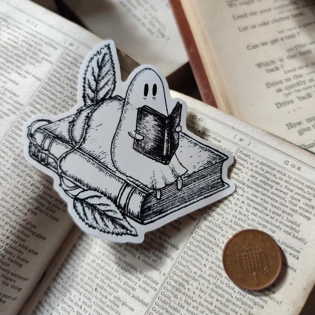 A studious little ghostie catching up on a bit of reading, on a lovely die-cut vinyl sticker, from an original ink illustration by Jon Turner.