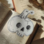 A little ghostie with a flower, perched atop a spooky skull, on a die-cut vinyl sticker. From original ink artwork by Jon Turner.