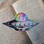 A spooky little UFO on a lovely die-cut holographic vinyl sticker from original pen and ink artwork by Jon Turner.