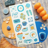 🩴🍊 @papergrapeprints is serving up a sun-soaked spread of seaside favorites, and we’ll take one of everything! Bright oranges, sardines, pasta, pretty ceramics, hydrangeas, and that perfect blue crab come together in a dreamy mix of coastal color and vacation-day charm. Add flip-flops, something cold to sip, and absolutely zero plans. Art by: @papergrapeprints

Top Coating: None
Adhesive Layer: Paper
Backing Layer: Clear PET
6.69" x 3.54".
Weight - 0.03lbs
1 sheet included