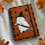 A new A5 notebook featuring a ghost dressing up as a witch!

This hardcover notebook comes lined and with an elastic band. There are 96 double sided pages.