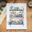 Postcard featuring my original watercolor and ink illustration of the oddities, books, and mushrooms tucked away in the shelves of a forest witch, including a mischievous raccoon, a wise owl, and a box of potions.