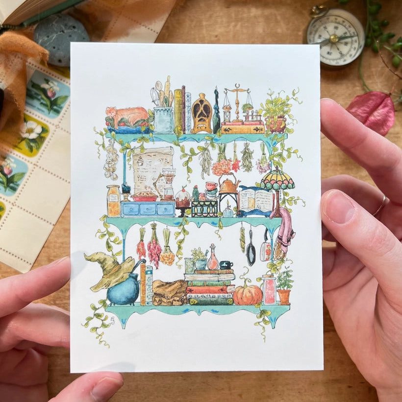 Postcard featuring my original watercolor and ink illustration of the oddities, books, tools, and trinkets tucked away in the shelves of a kitchen witch, including a sweet cat and a stained glass lamp.