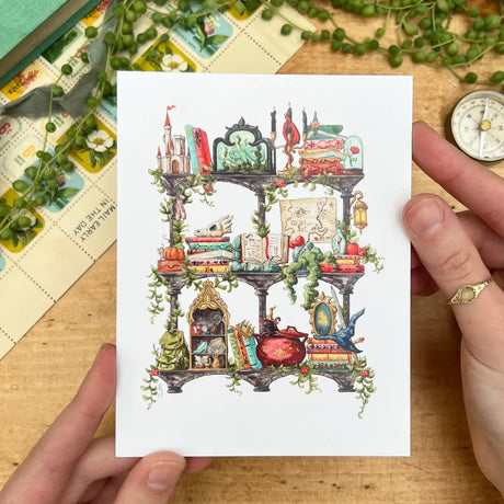 Postcard featuring my original watercolor and ink illustration of the various enchanted items collected by a storybook witch as she travels throughout all your favorite fairytales, including a charming castle, a glass-encased rose, and a brightly colored dragon, all nestled on stone shelves that evoke mysterious castle corridors covered in rose vines.