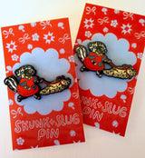 A Skunk and their friend the Slug take a walk through the forest.

This hard enamel pin measures approximately 1.75" and features a rubber clasp for easy closure and two back posts so pin stays where you stick it. Comes with a back card.
