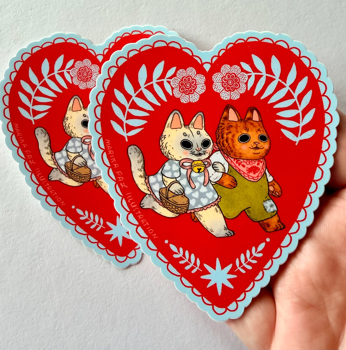 Two cats go for a walk on this folk art inspired sticker.

This vinyl matte sticker is weather and waterproof-stick it on a notebook, bike, or car- it's going to stick around! Heck, throw it on a water bottle and through the dishwasher. This sticker can go anywhere. Sticker measures 3.5" x 4.5" Printed in USA.