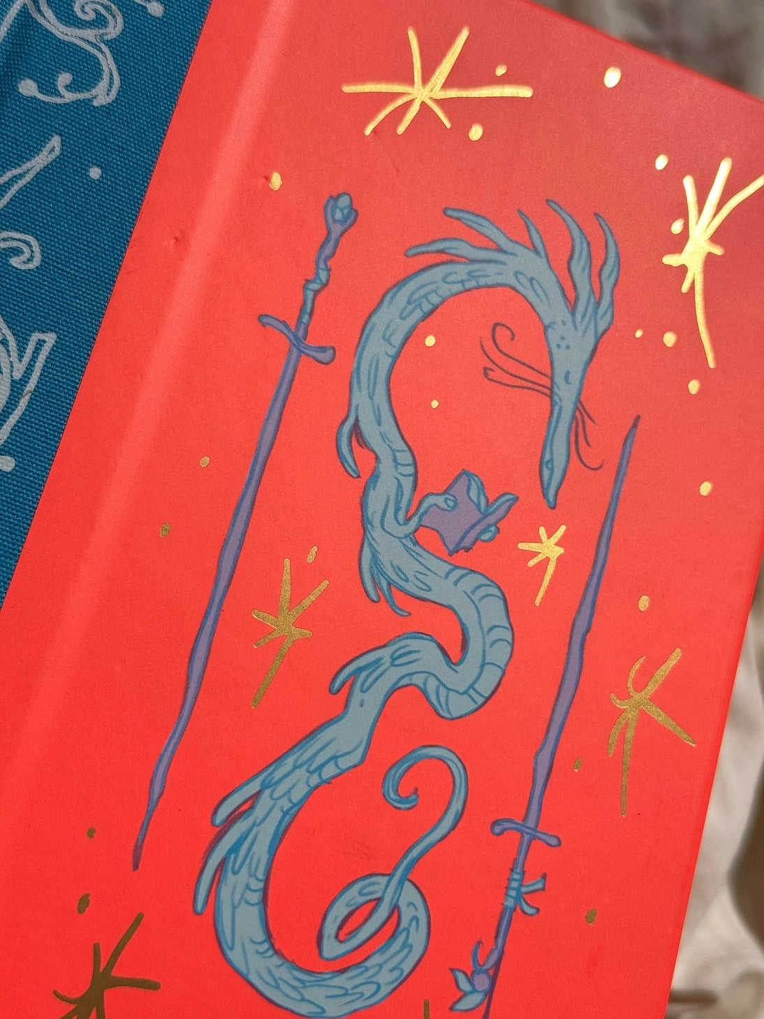 This is a blank 200 page notebook/sketchbook with thin ivory Munken paper perfect for light sketching or writing. Part of a fantasy collection called Woodfolk.

The cover is fluorescent pink/orange and has a smooth matte finish with gold foiling on the front and back. Plus it has a blue fabric spine with white embossing, adding to the charm of the book. Best for pencils, light pens, and generally light mediums, as thick markers or water can bleed. Not recommended for gouache or heavy marker use.