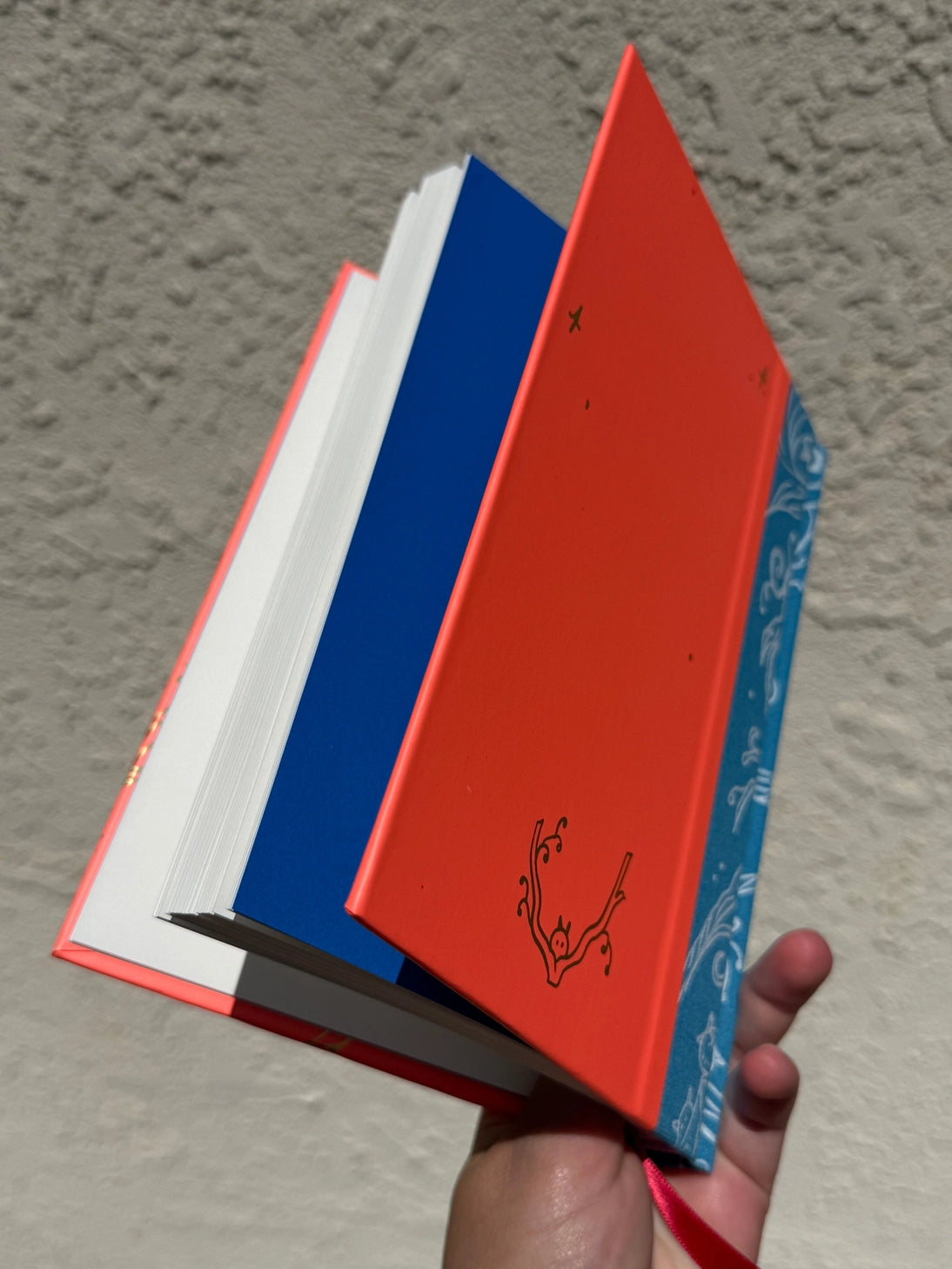 This is a blank 200 page notebook/sketchbook with thin ivory Munken paper perfect for light sketching or writing. Part of a fantasy collection called Woodfolk.

The cover is fluorescent pink/orange and has a smooth matte finish with gold foiling on the front and back. Plus it has a blue fabric spine with white embossing, adding to the charm of the book. Best for pencils, light pens, and generally light mediums, as thick markers or water can bleed. Not recommended for gouache or heavy marker use.