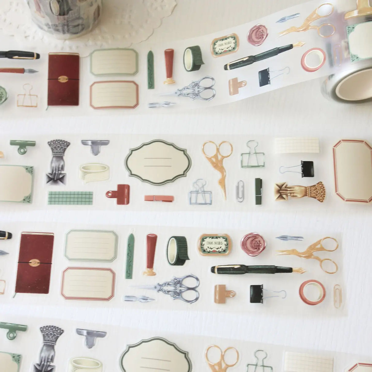 An updated version of our Stationery Essentials PET tape, now with a longer 50cm designer loop for even more creative possibilities.

This PET tape features hand-painted illustrations of vintage stationery such as wax seal stamps, fountain pens and ornate scissors. Designed by Rebecca and pre-cut for effortless use, it's perfect for journaling, collaging and adding a vintage aesthetic to any creative project.

Extra wide at 50mm with a matt transparent finish that layers cleanly over any background. No scis