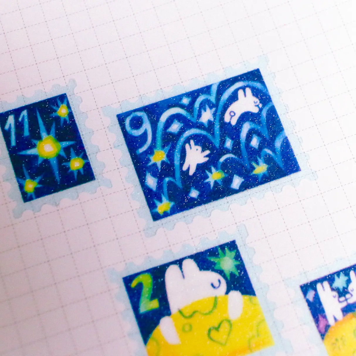 'To the Moon &amp; Back' Frosted Glitter Transparent A6 Sticker Sheet. Stickers are stamp shaped and have a clear blue background.

Not waterproof.
Do not place in areas of high wear (laptops, phone cases, water bottles, etc).
Sticker sheets come packaged in a plastic sleeve.