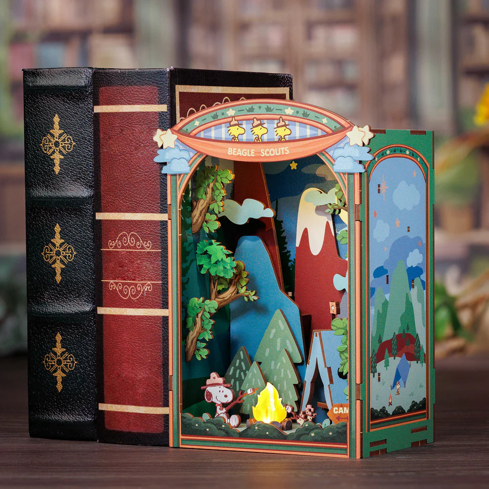 Gather 'round the campfire with Snoopy and his loyal Beagle Scouts in this heartwarming DIY Miniature Book Nook Kit! Nestled between trees and under the stars, Snoopy and the Woodstocks are toasting marshmallows over a crackling fire, their cozy tent pitched nearby. In the distance, gentle mountain silhouettes rise beyond the forest-setting the perfect scene for a peaceful, storybook escape.

This delightful book nook brings the charm of classic Peanuts adventures and the joy of outdoor camping into a beaut