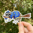 A sticker with my illustration of a wizard raccoon riding on a broom.

This die-cut vinyl sticker is durable and perfect for water bottles, notebooks, laptops, bikes, and all sorts of other surfaces! Make sure to clean and dry the surface thoroughly before applying.
