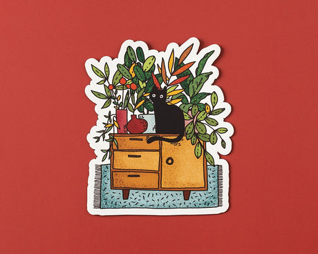 A cozy illustrated vinyl sticker featuring a curious black cat surrounded by lush houseplants and warm, homey details. Perfect for plant lovers, cat people, and anyone who enjoys calm, playful artwork.

🌟 Key Features:

• Dimensions: 3 x 2.5 inches&nbsp;

• High-quality vinyl material

• Waterproof and weather-resistant

• Ideal for personalizing any surface