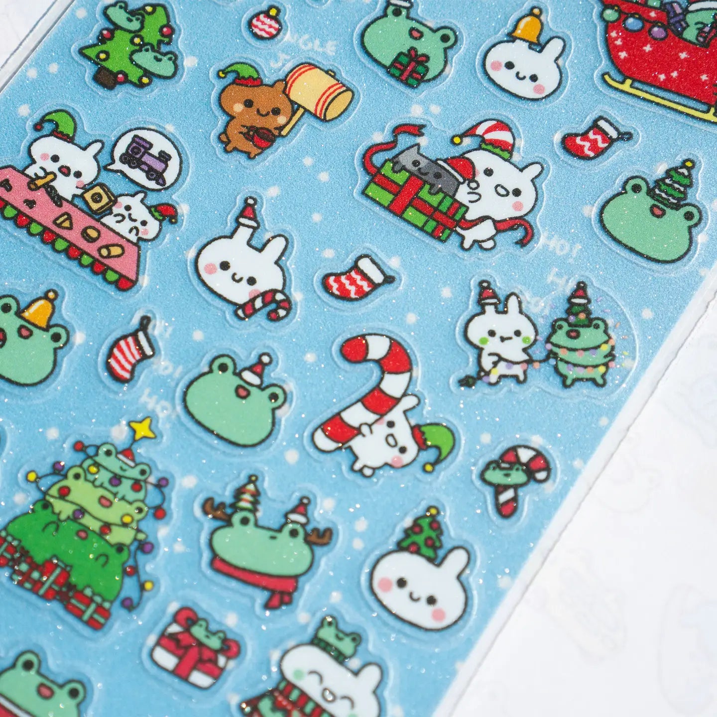 This is part of a new series of sticker sheets that feature different "days".

There are 33 individual glitter stickers on the sheet full of holiday joy!

They are plastic stickers on a frosted plastic sheet with a backing card and packaging that's ready to display.