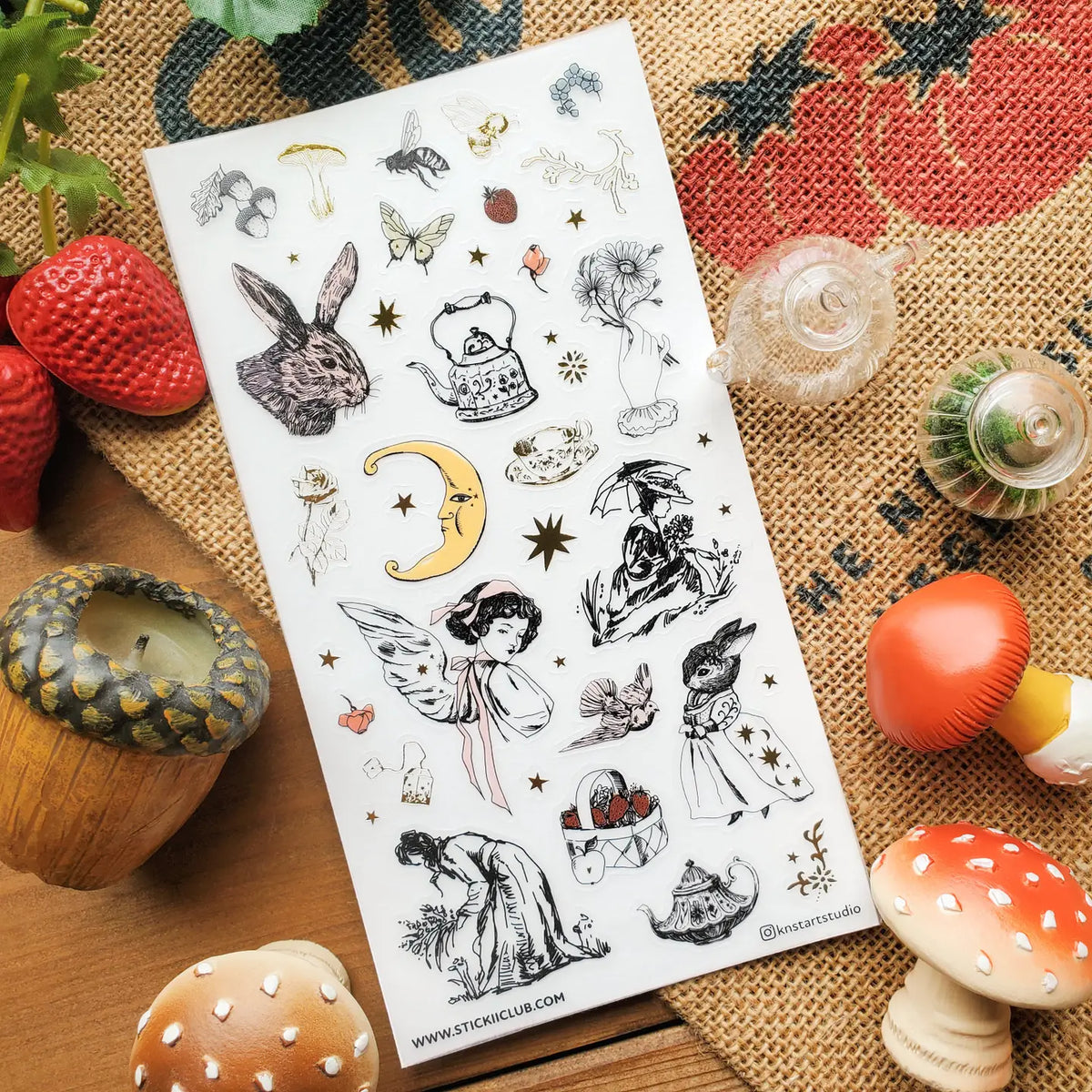 🐇🫖 Somewhere between an old garden journal and a moonlit tea party, @knstartstudio’s enchanting sheet features rabbits in little outfits, winged maidens, buzzing bees, mushrooms, strawberries, roses, and ornate teapots. It’s cottage life with a hint of folklore, perfect for anyone who loves their farmhouse days served with tea leaves, wildflowers, and a little moonlight.

Art by: @knstartstudio

One sticker sheet is included.
• Top Coating: Gold foil
• Adhesive Layer: Washi
• Backing Layer: Clear PET
• 6.
