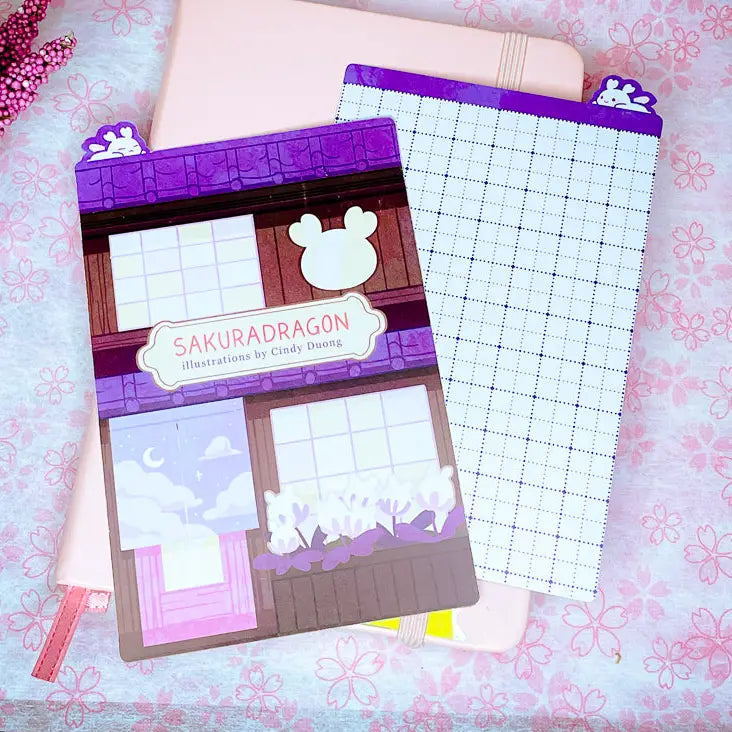 Sakuradragon - Sakura Street A6 Pencil Board

A napping Sakuradragon perched onto of a cozy little shop Sakura Street. It's almost as if she is sleeping on top of your notebook.

What is a pencil board?
Pencil boards are inserts for your notebook that sit under the page you are writing on. They prevent indents on the next page when you write and even prevent ink from bleeding through to the page beneath. But honestly, they can just be cute bookmarks.