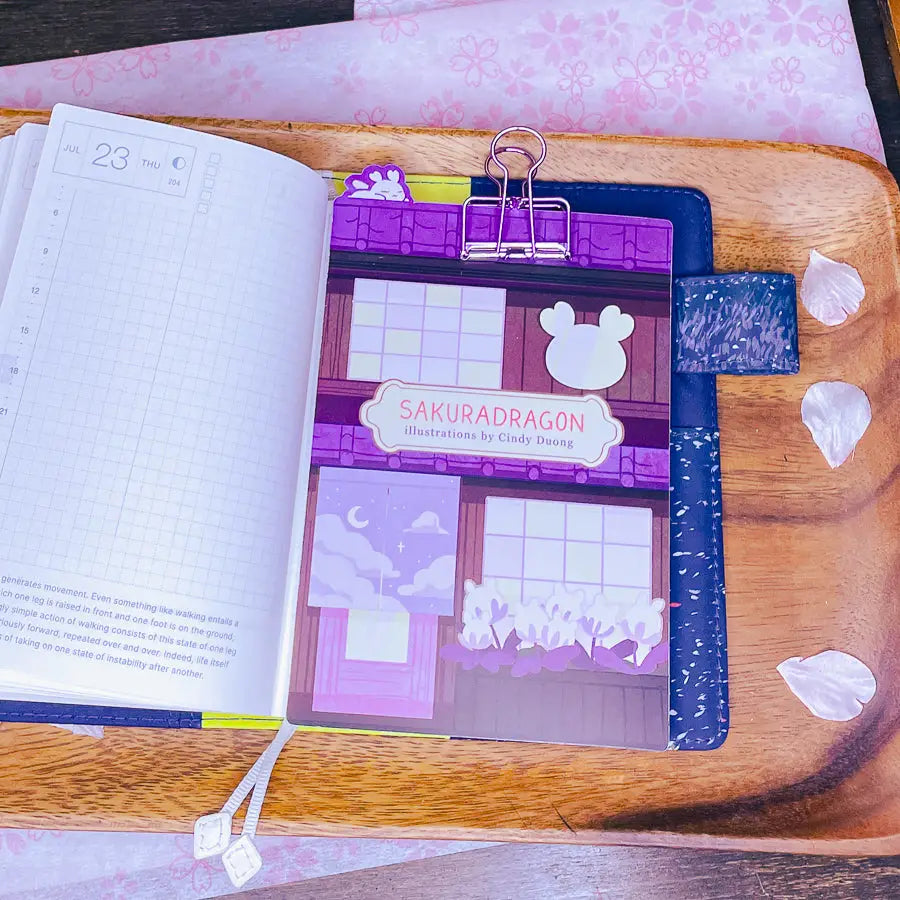 Sakuradragon - Sakura Street A6 Pencil Board

A napping Sakuradragon perched onto of a cozy little shop Sakura Street. It's almost as if she is sleeping on top of your notebook.

What is a pencil board?
Pencil boards are inserts for your notebook that sit under the page you are writing on. They prevent indents on the next page when you write and even prevent ink from bleeding through to the page beneath. But honestly, they can just be cute bookmarks.
