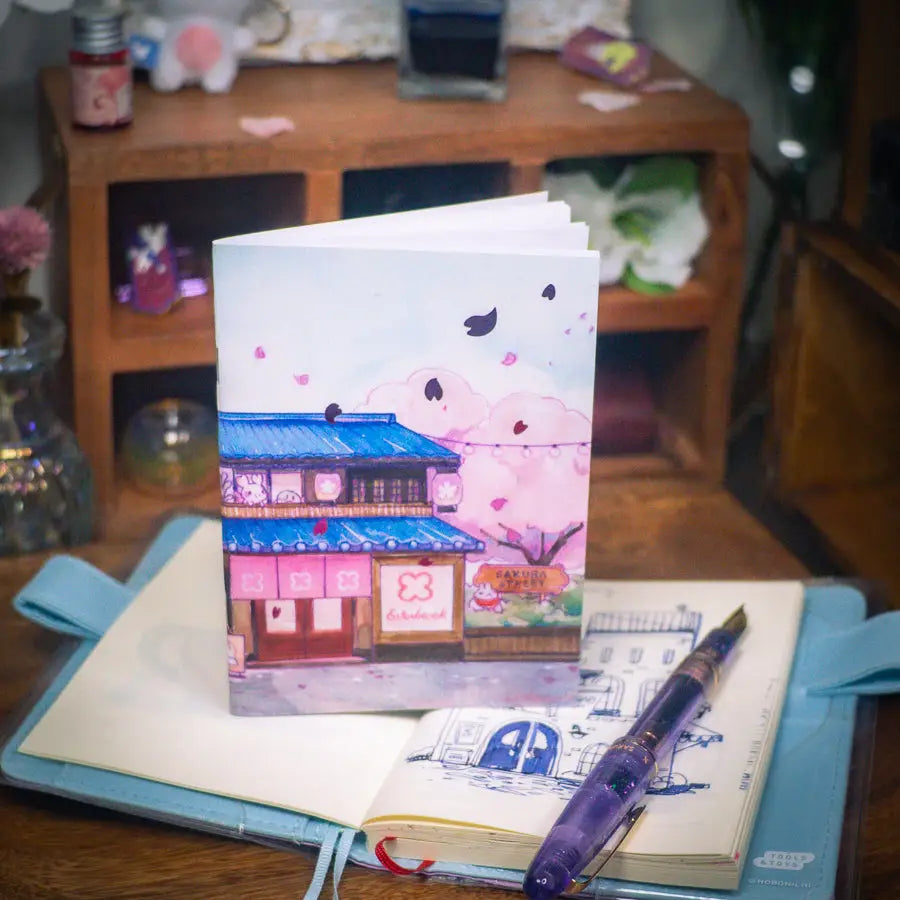 Sakuradragon - Sakura Street Shopfronts A6 Notebook

Cozy little shop fronts that you will find on your walk down Sakura Street. Did you notice the pink foil cherry blossoms falling from the sky?

Dimensions: &nbsp;A6 (10.5 × 14.8 cm)
Paper: Double-sided offset paper
Page Ruling: Blank
Pages: 64


Message from sakuradragon: &nbsp;Not all paper and ink are made equal but this paper does a great job with both fountain pens and dip pens. There is minimal ghosting but bleeding does occur with heavy ink usage.