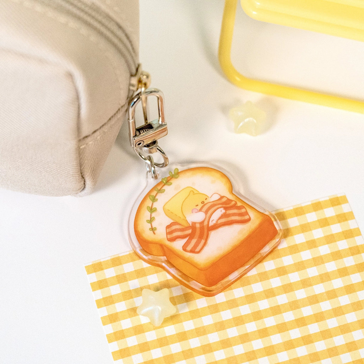 The Sweet Dreams keychains feature Muffin Corner characters sleeping on top of some of their favorite foods. Devyegg is sleeping a warm piece of toast after a late night of working.

Details:

Approximate Dimensions: 1.6” x 1.8” (4.1cm x 4.4cm)&nbsp;
Material: Acrylic
Double-sided
Comes with 1 Keychain