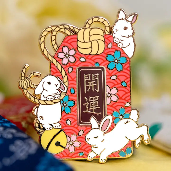 Japanese omamori surrounded by white rabbits! An “omamori” is a good luck charm that is said to provide various forms of luck and protection. These protective charms can come in a variety of different types including luck for health, school, work, or love! This charm has the word “Kaiun” 開運 on it which means “better fortune” or a general “good luck” interpretation.

✦ Hard enamel
✦ Shiny gold metal
✦ 2 inches
✦ 2 Posts for extra security
✦ Rubber backings
✦ Back stamped for authenticity

Comes packaged on a