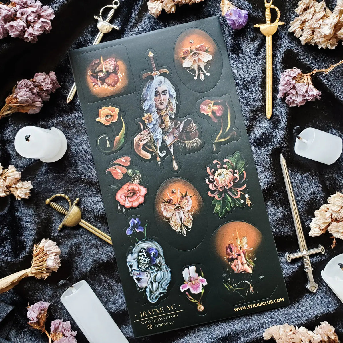In @iratxe.yc’s shadowed garden, nothing is quite as it first appears. Jeweled flowers gaze back from curling stems, delicate moths wear watchful eyes, and a silver-haired guardian stands adorned in blossoms, gemstones, and armor. Rich with surreal beauty and dark botanical magic, this striking sheet reveals a forest where every petal may be hiding a secret.

Art by: @iratxe.yc

One sticker sheet is included.
Top Coating: None
Adhesive Layer: Paper
Backing Layer: Clear PET
Size:6.69"x3.54"
Weight-0.03oz
