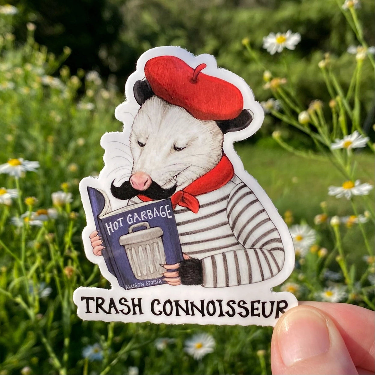 Only the finest reading material will do for this discerning beret-and-neckerchief-clad opossum! That's why he's smirking with satisfaction while perusing his well-loved copy of Hot Garbage at an outdoor café. (He picked up his beret, neckerchief, and striped boater shirt and afternoon espresso habit during a semester-long study abroad trip to Paris, which he'll tell you all about at length if you ask.)