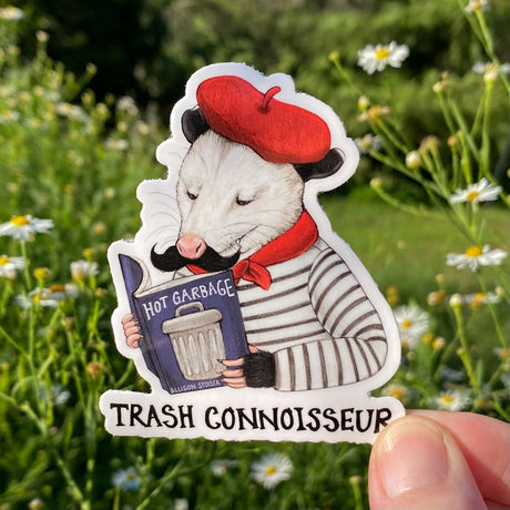 Only the finest reading material will do for this discerning beret-and-neckerchief-clad opossum! That's why he's smirking with satisfaction while perusing his well-loved copy of Hot Garbage at an outdoor café. (He picked up his beret, neckerchief, and striped boater shirt and afternoon espresso habit during a semester-long study abroad trip to Paris, which he'll tell you all about at length if you ask.)