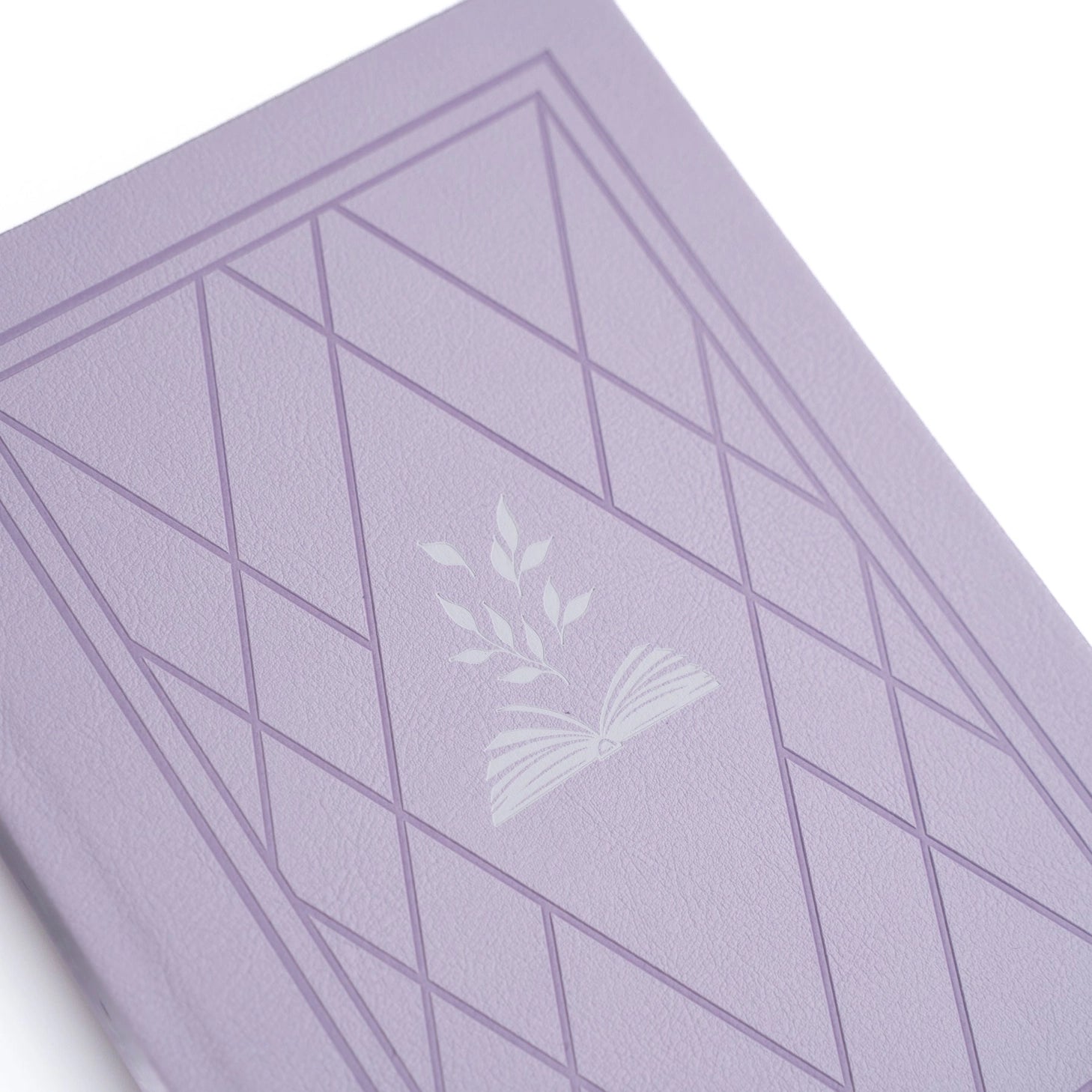 A dreamy notebook in gentle lilac vegan leather, inspired by classic library bindings. Subtle geometric embossing frames a delicate open-book motif, creating a clean, elegant design that appeals to book lovers, writers, and everyday creatives.