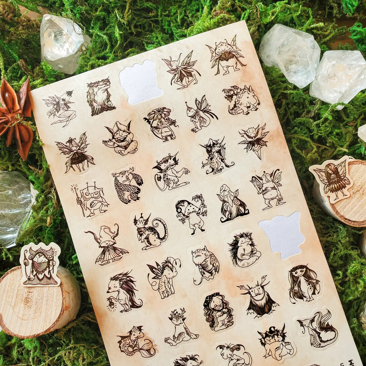  A curious gathering of tiny forest folk fills this sheet, from winged fae and horned creatures to mushroom dwellers, leafy little beings, and a few faces that are wonderfully hard to classify. Delicate sepia linework gives each character its own personality, creating an enchanting collection that feels as though these secretive little residents have been hiding among the moss all along.

One sticker sheet is included.
Top Coating: None
Adhesive Layer: Paper
Backing Layer: Paper
Size: 6.69"x3.54"
Weight-0.3