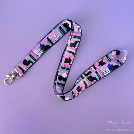 Bookish Witch Cat Lanyard. This purple lanyard features witch cats and books, perfect for all cat lovers out there. Show off your love for felines while keeping your items secure and easily accessible.

2cm X 95cm
double-sided printing
Swiveling Lobster Clasp