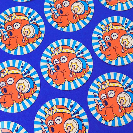 Takotarô is one of our original characters. It is inspired by the mascots that can be found on the front of takoyaki stands, these small balls of dough filled with octopus.
The name Takotaro is composed of the Japanese word “tako” which means “octopus” and the suffix “tarô” which means “eldest son” and which is added to many Japanese first names.
He can be seen here playing the taiko, which means “drum” in Japanese.

• Vinyl sticker
• 6.2 x 6.2 cm
• PVC-free
• Anti-UV varnish
• Can be used outside
• Printed